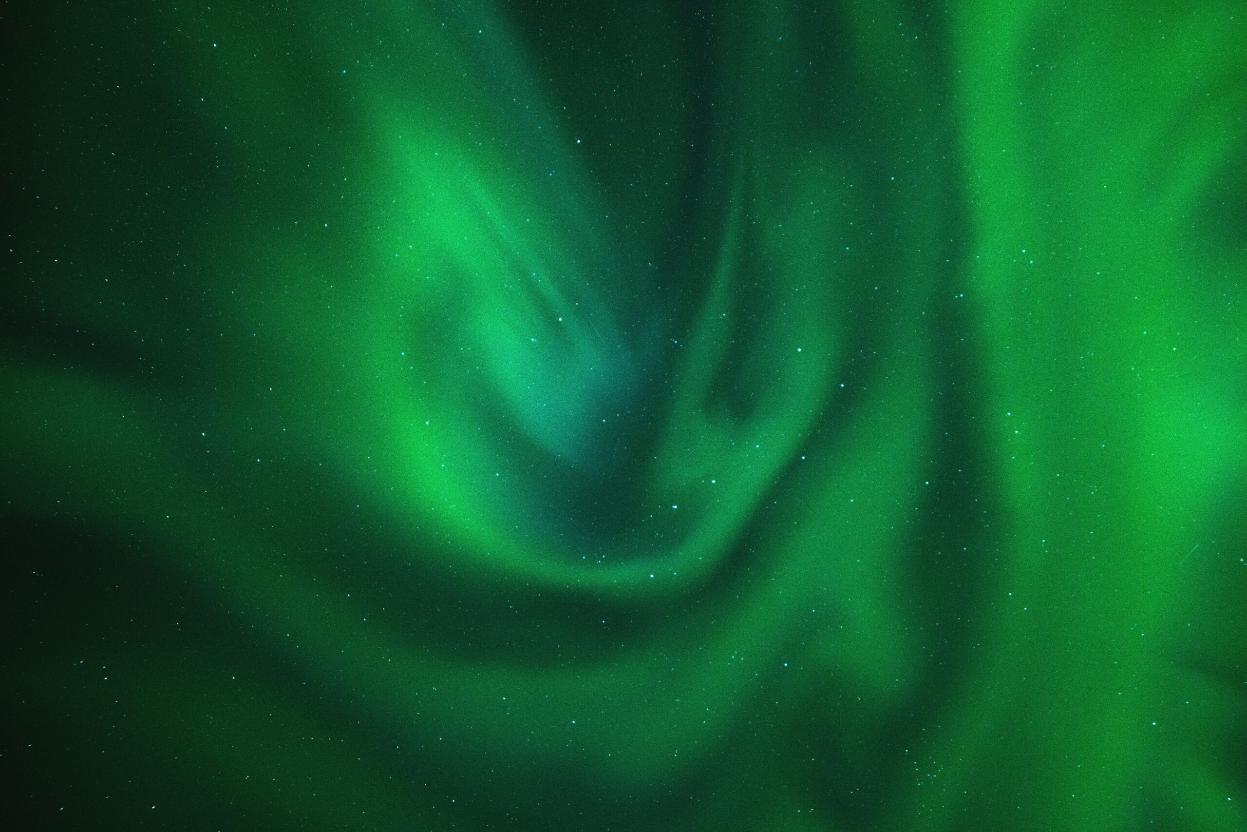 Vibrant green Northern Lights swirling across a dark starry night sky.